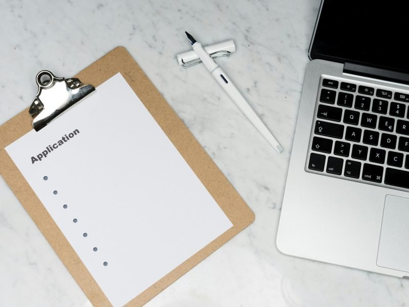 white paper on brown folder beside silver laptop computer